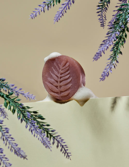Lavender soap covered in foam, surrounded by lavender leafs