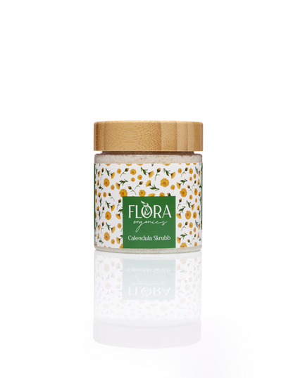 Flora Organics Calendula Scrub in glass jar with bamboo lid, reflected on white background