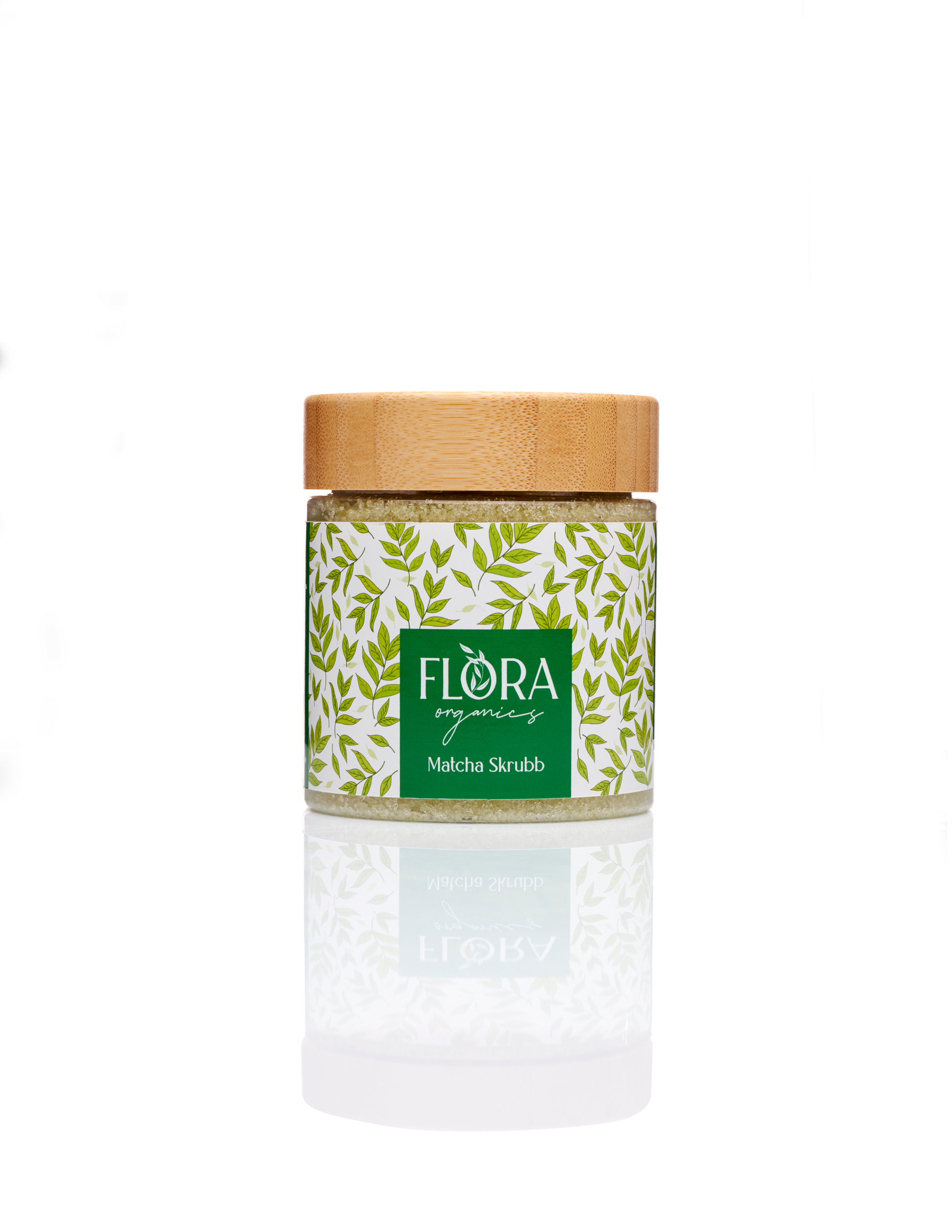 Flora Organics Matcha Scrub in glass jar with bamboo lid, reflected on white background